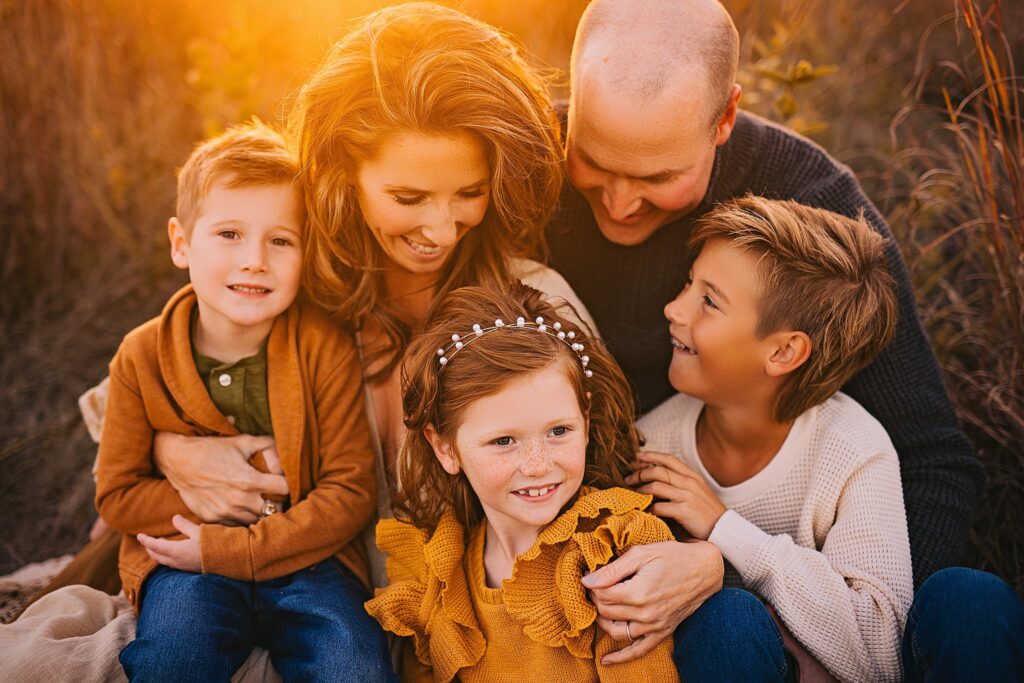 A family snuggles together in the warmth of sunset at a family photo session
