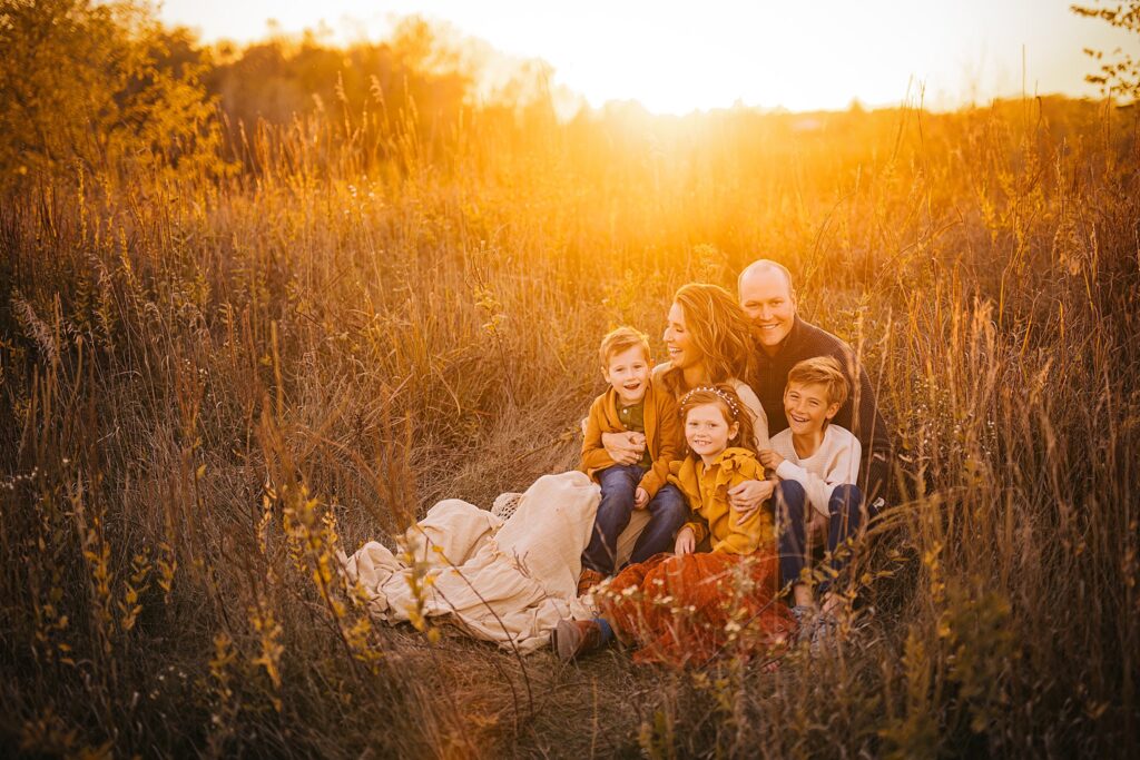 A family snuggles together in the warmth of sunset at a family photo session