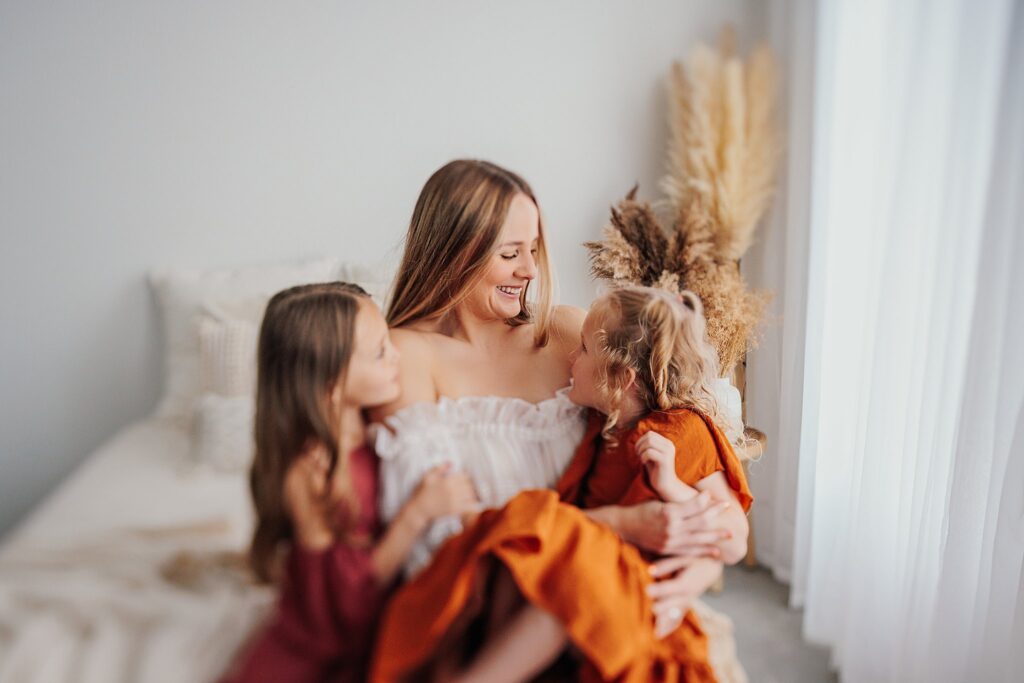 Mother and her two daughters sharing sweet moments during a Mommy and Me session in a Cedar Falls, Iowa studio