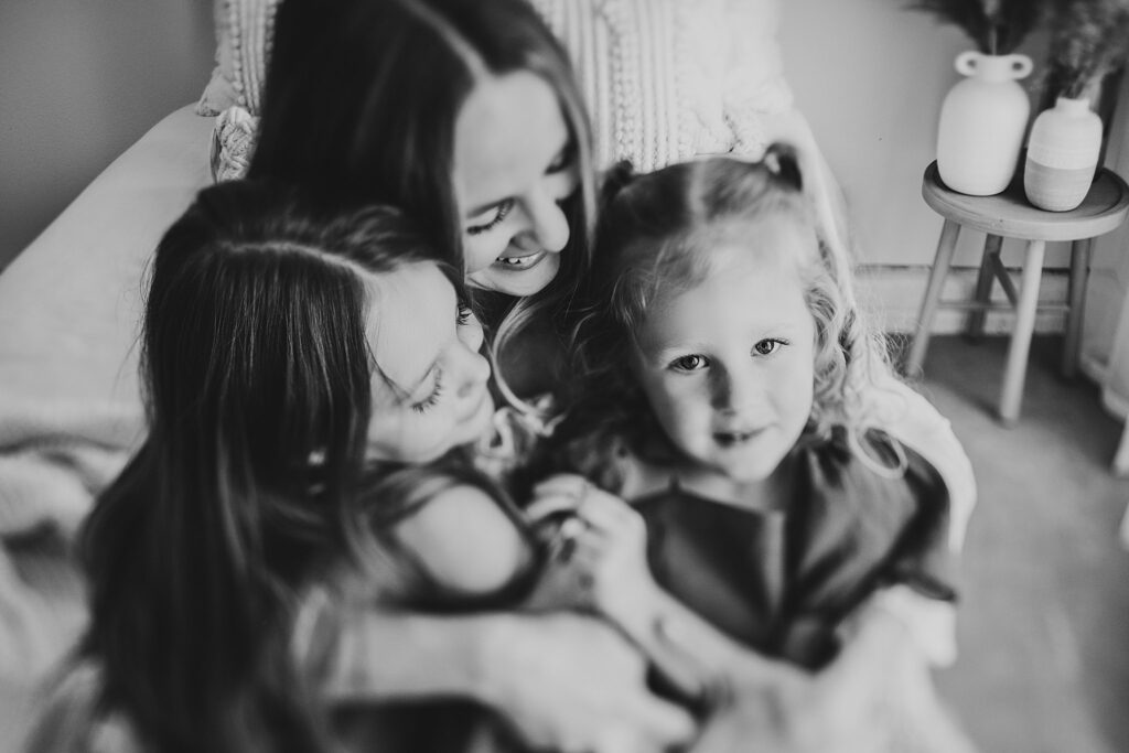 Mother and her two daughters sharing sweet moments during a Mommy and Me session in a Cedar Falls, Iowa studio