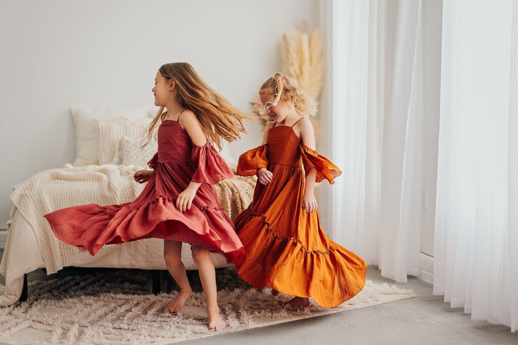 Beautiful sibling portrait of two sisters smiling and dancing together during a family photography session