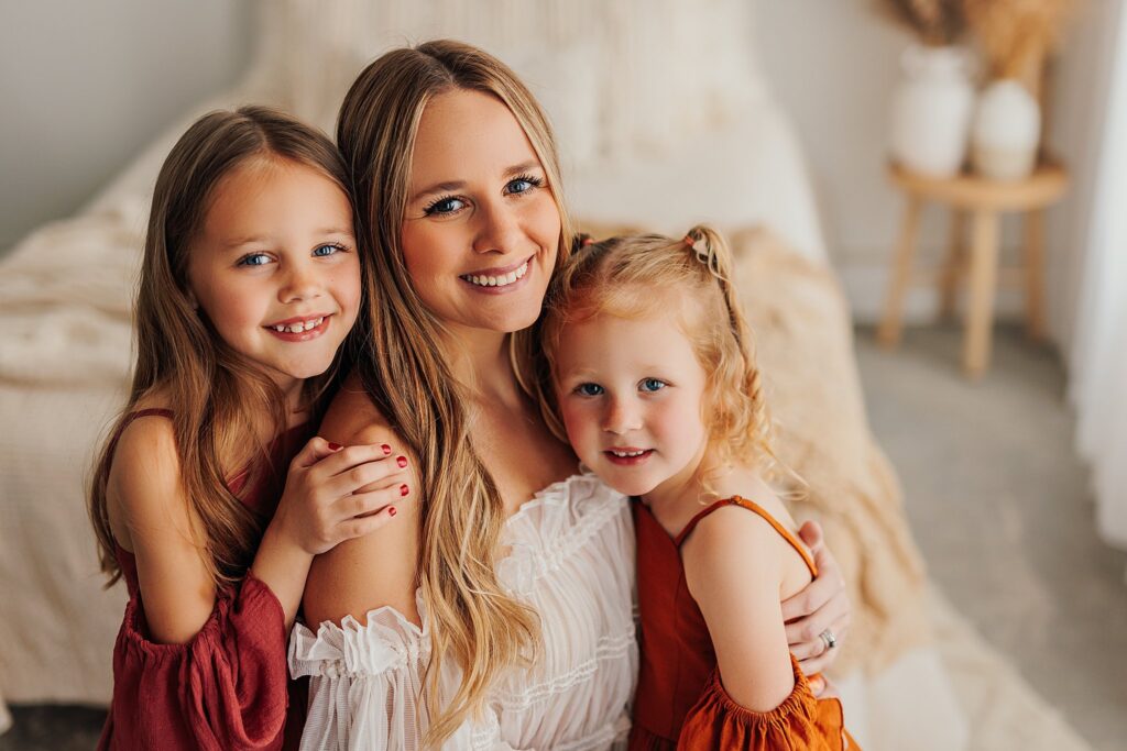 Mother and her two daughters sharing sweet moments during a Mommy and Me session in a Cedar Falls, Iowa studio