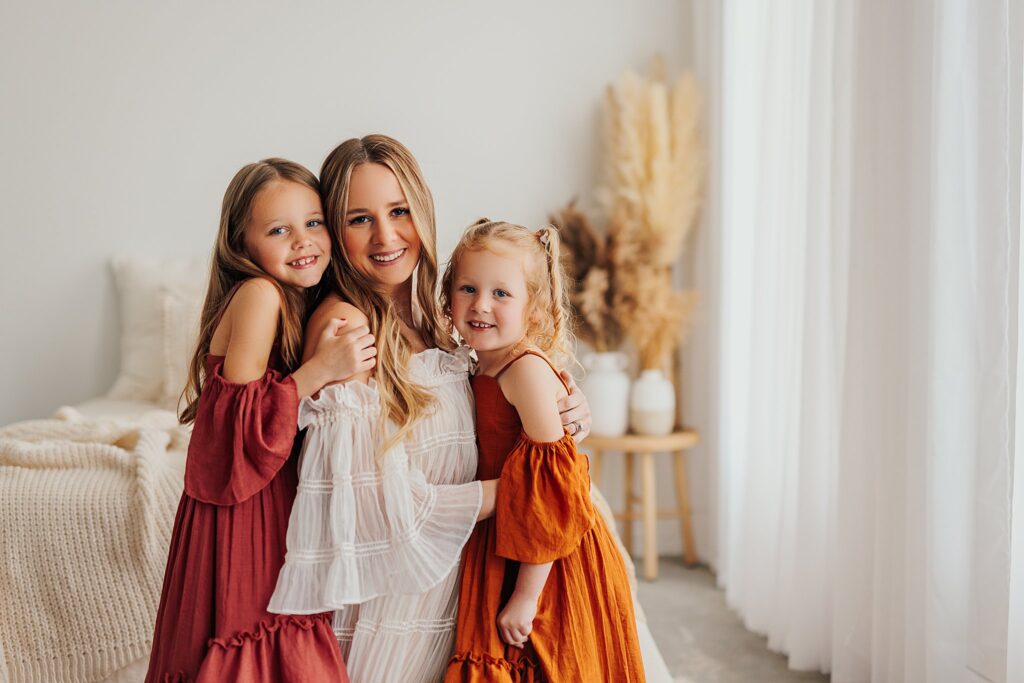 Mother and her two daughters sharing sweet moments during a Mommy and Me session in a Cedar Falls, Iowa studio