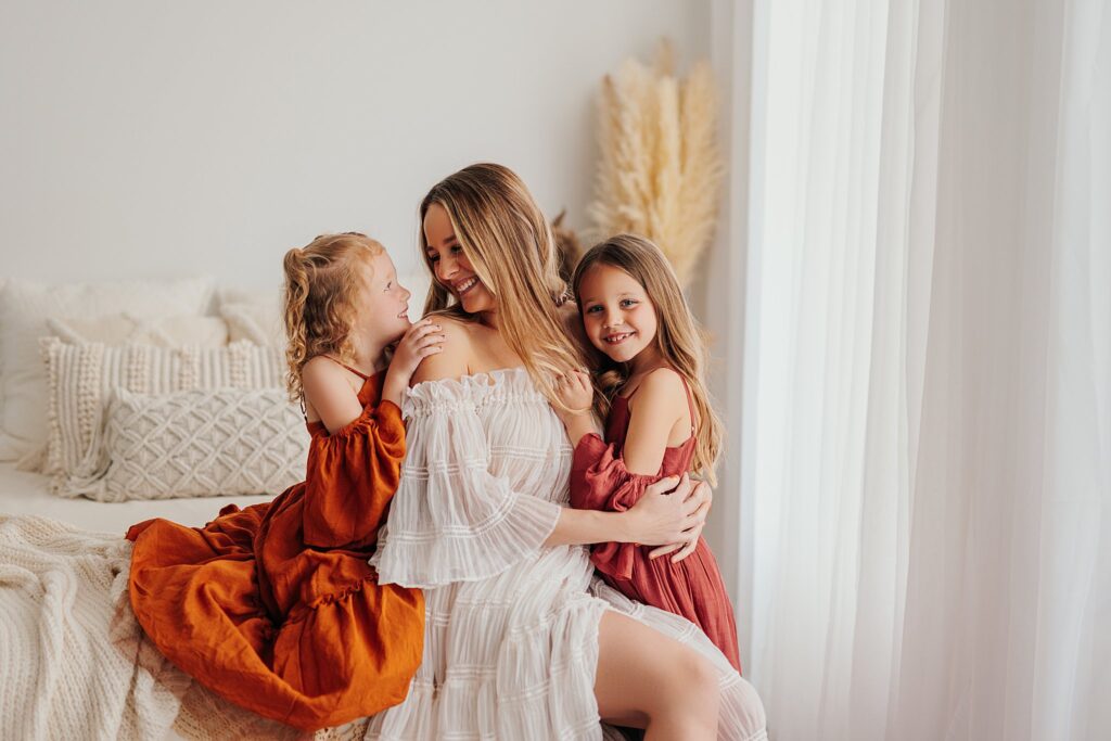 Mother and her two daughters sharing sweet moments during a Mommy and Me session in a Cedar Falls, Iowa studio