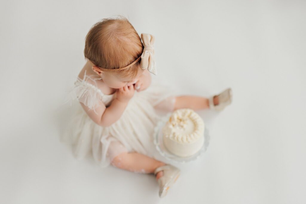 One-year-old baby enjoying a cake smash session with fresh florals in a Cedar Falls, Iowa photography studio