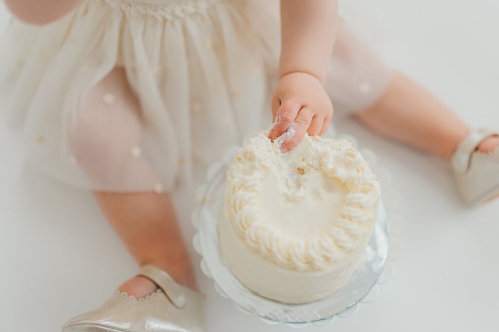 One-year-old baby enjoying a cake smash session with fresh florals in a Cedar Falls, Iowa photography studio