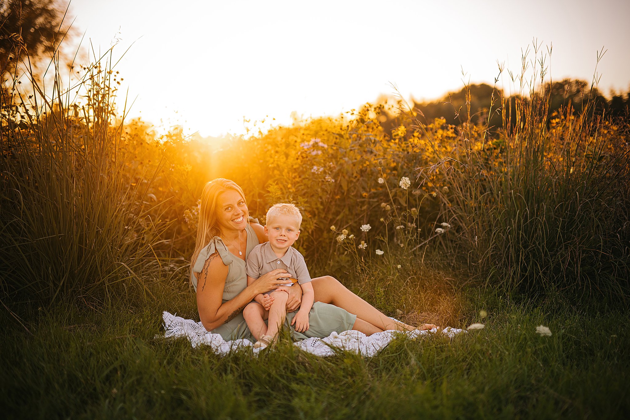 a young boy snuggles his mom at sunset