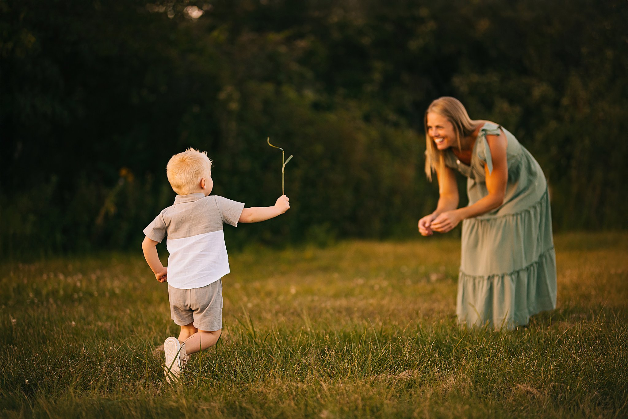 a young boy runs to his mother with a twig or leaf or grass